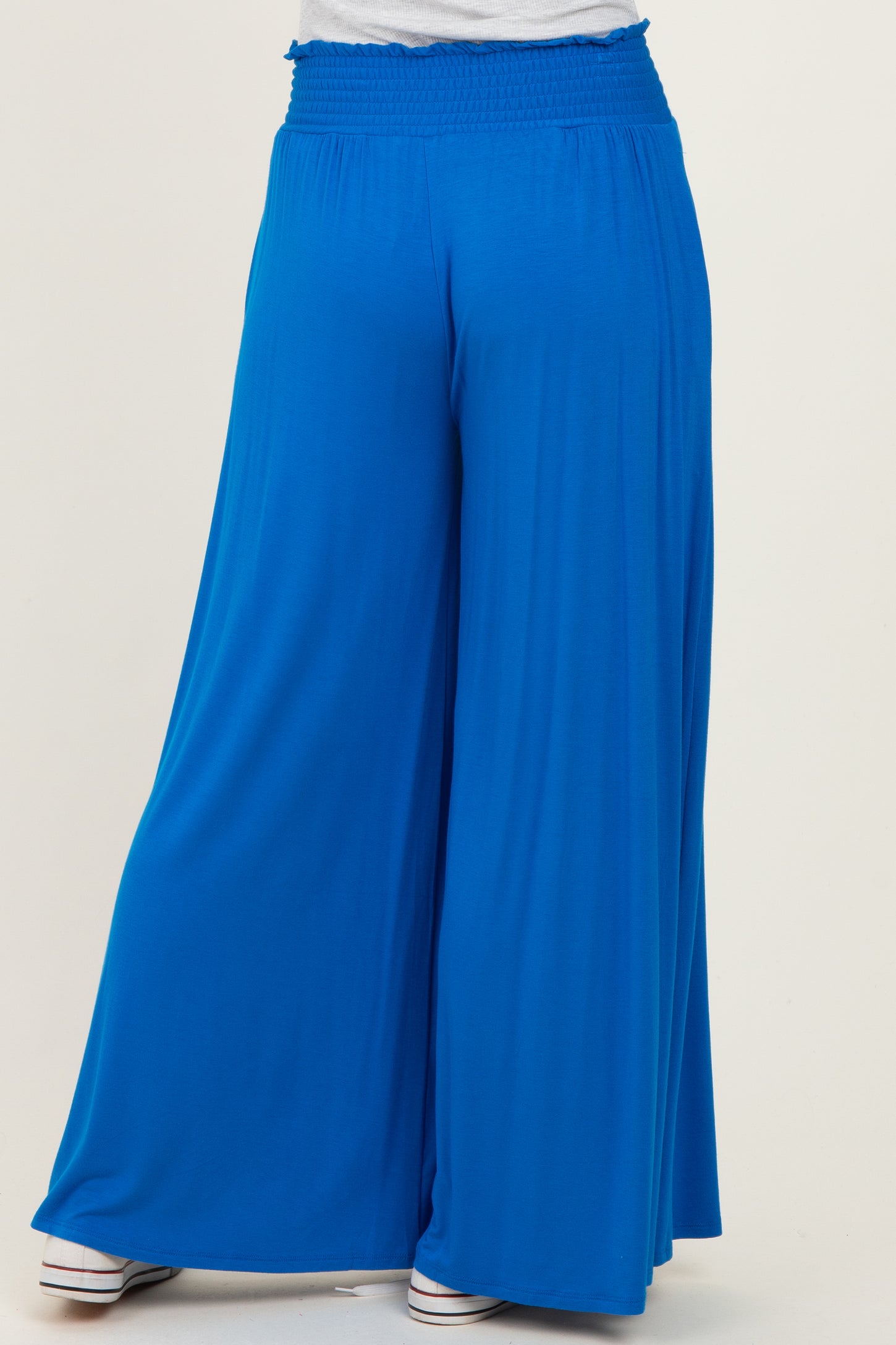 woman wearing a pair of bright blue wide-leg pants with a smocked waistband