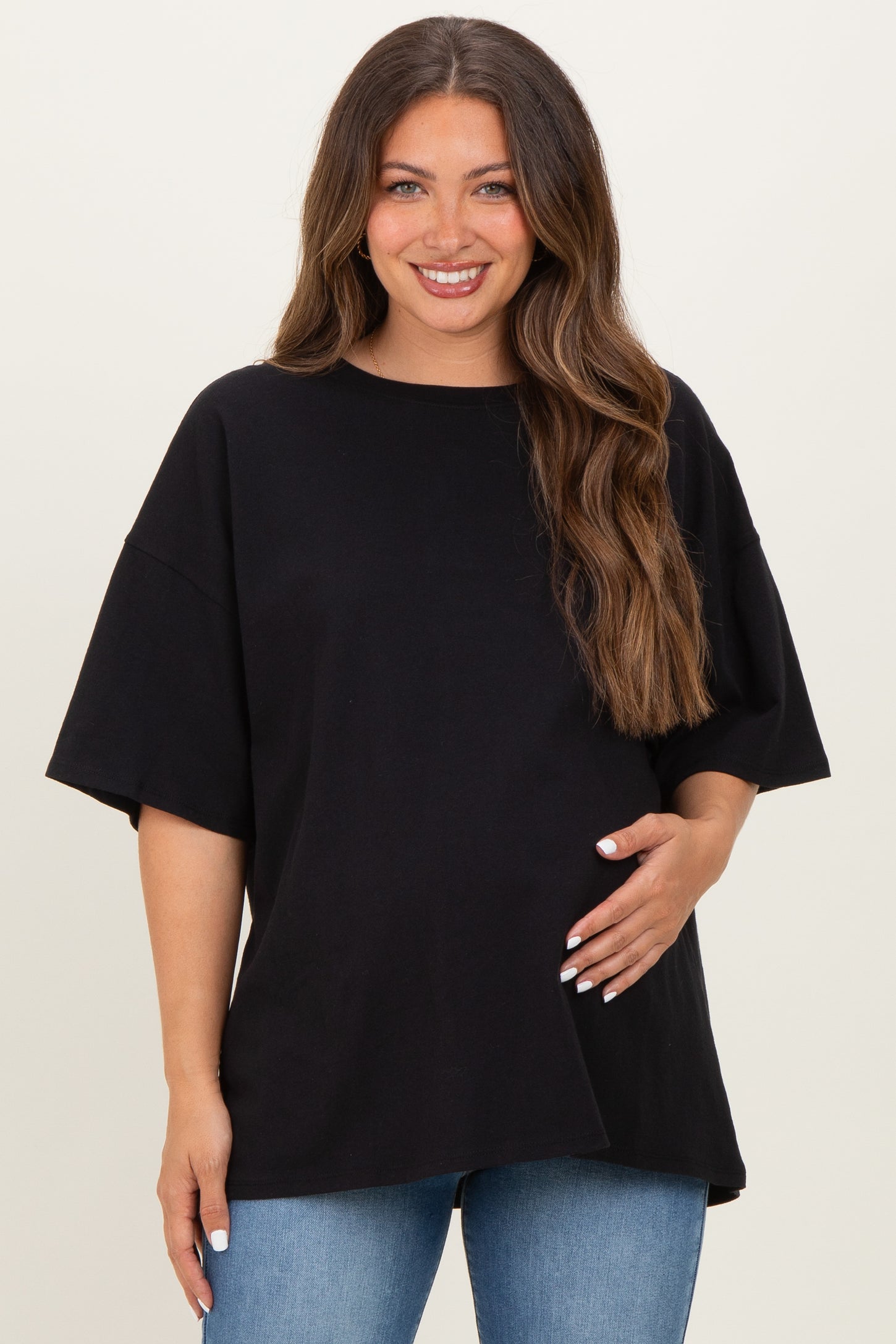 woman wearing a black maternity top with short sleeves and a relaxed fit, holding her baby bump