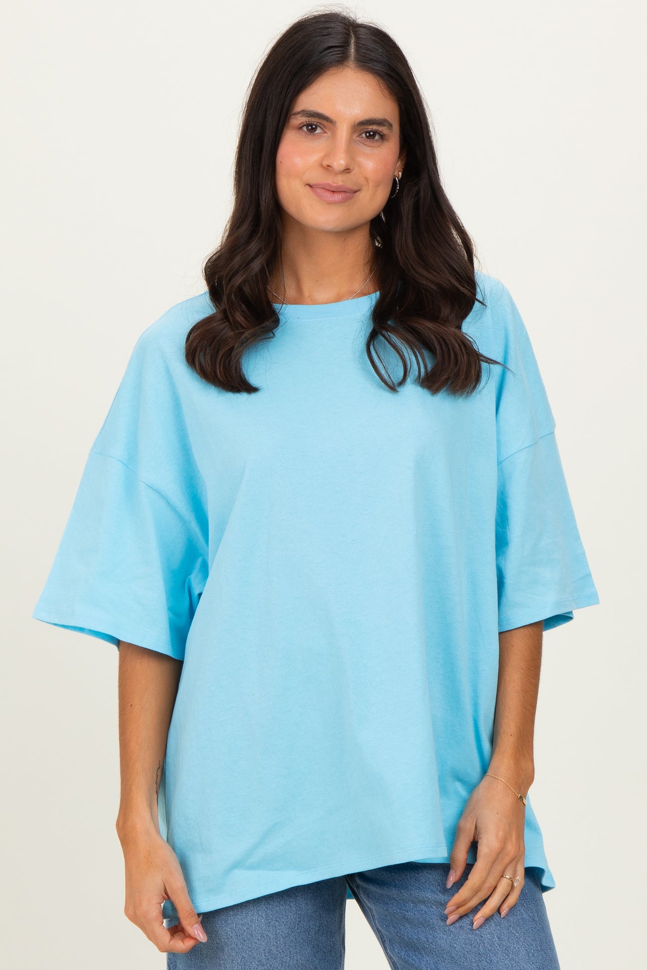 woman wearing an oversized light blue t-shirt with short sleeves and a relaxed fit, paired with jeans
