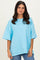 woman wearing an oversized light blue t-shirt with short sleeves and a relaxed fit, paired with jeans