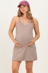 woman wearing a taupe maternity dress with pockets and holding her baby bump