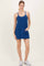 woman wearing a dark blue sleeveless casual dress with pockets and white sneakers