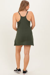 woman wearing a dark green maternity dress with adjustable straps, showing a relaxed fit and knee-length style from the back