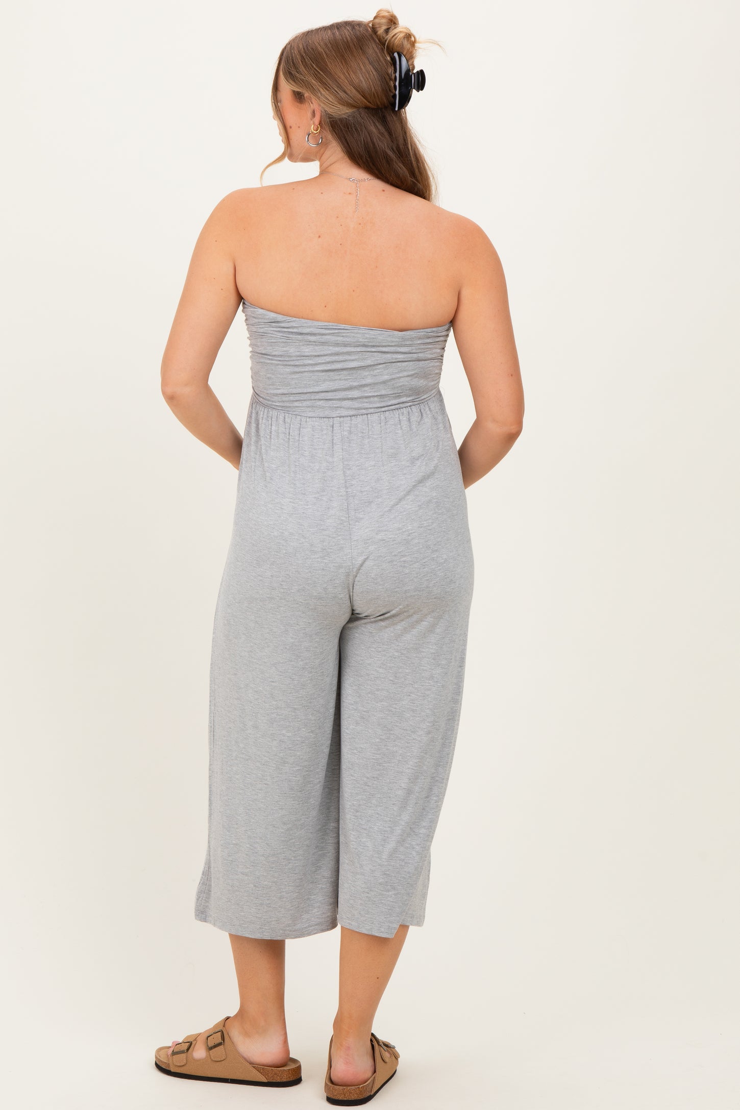 woman wearing a gray strapless maternity jumpsuit with cropped legs, shown from the back