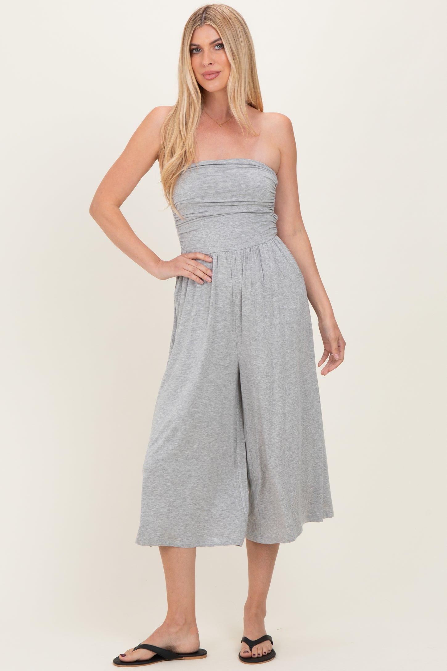 woman wearing a gray strapless jumpsuit with a fitted bodice and wide-leg pants
