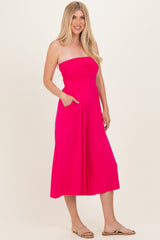 woman wearing a bright pink strapless midi dress with side pockets and a fitted bodice