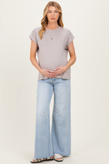 woman wearing a light gray short sleeve maternity top and light blue wide leg jeans with her baby bump visible