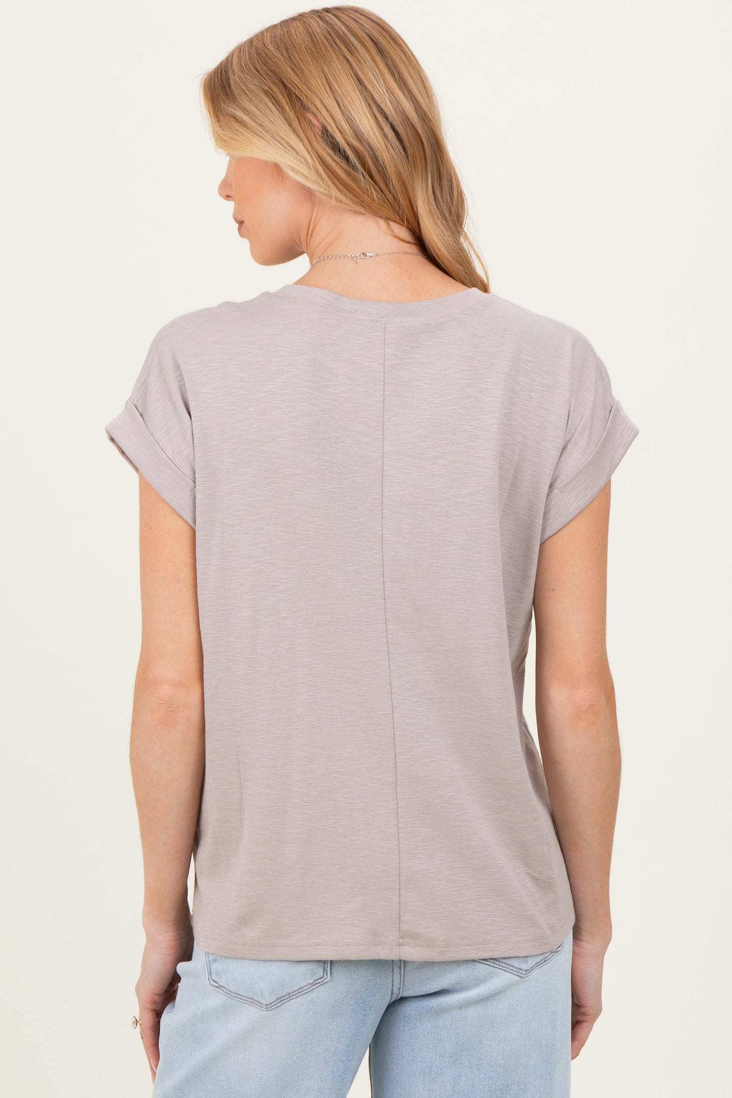 woman wearing a light gray maternity top with rolled short sleeves, showing the back view