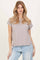 woman wearing a light gray short sleeve top with rolled cuffs and styled with light blue jeans