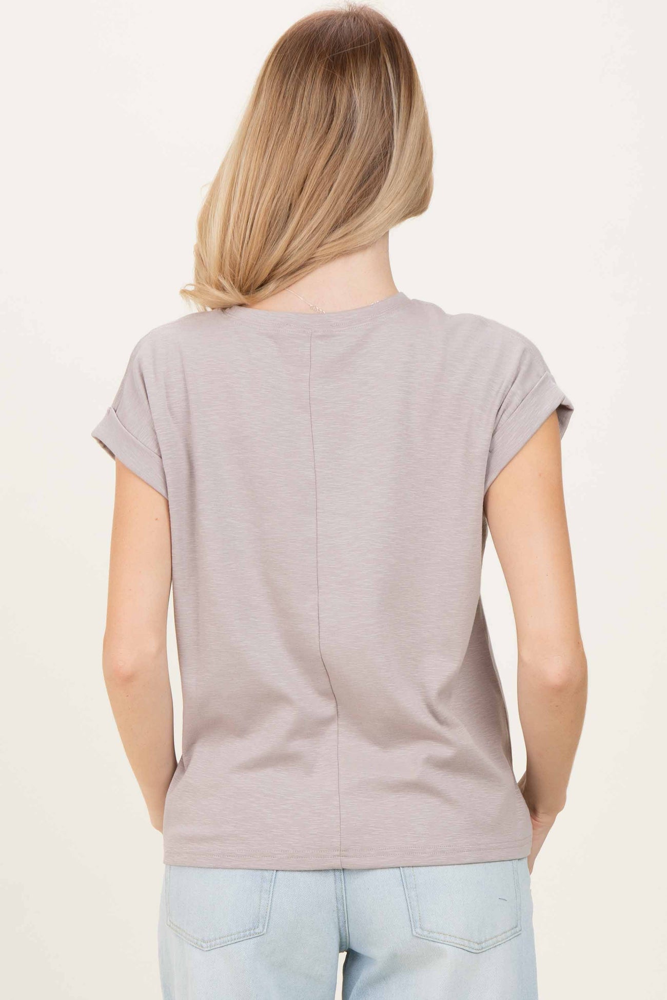 woman wearing a light gray short sleeve top with rolled cuffs, seen from the back