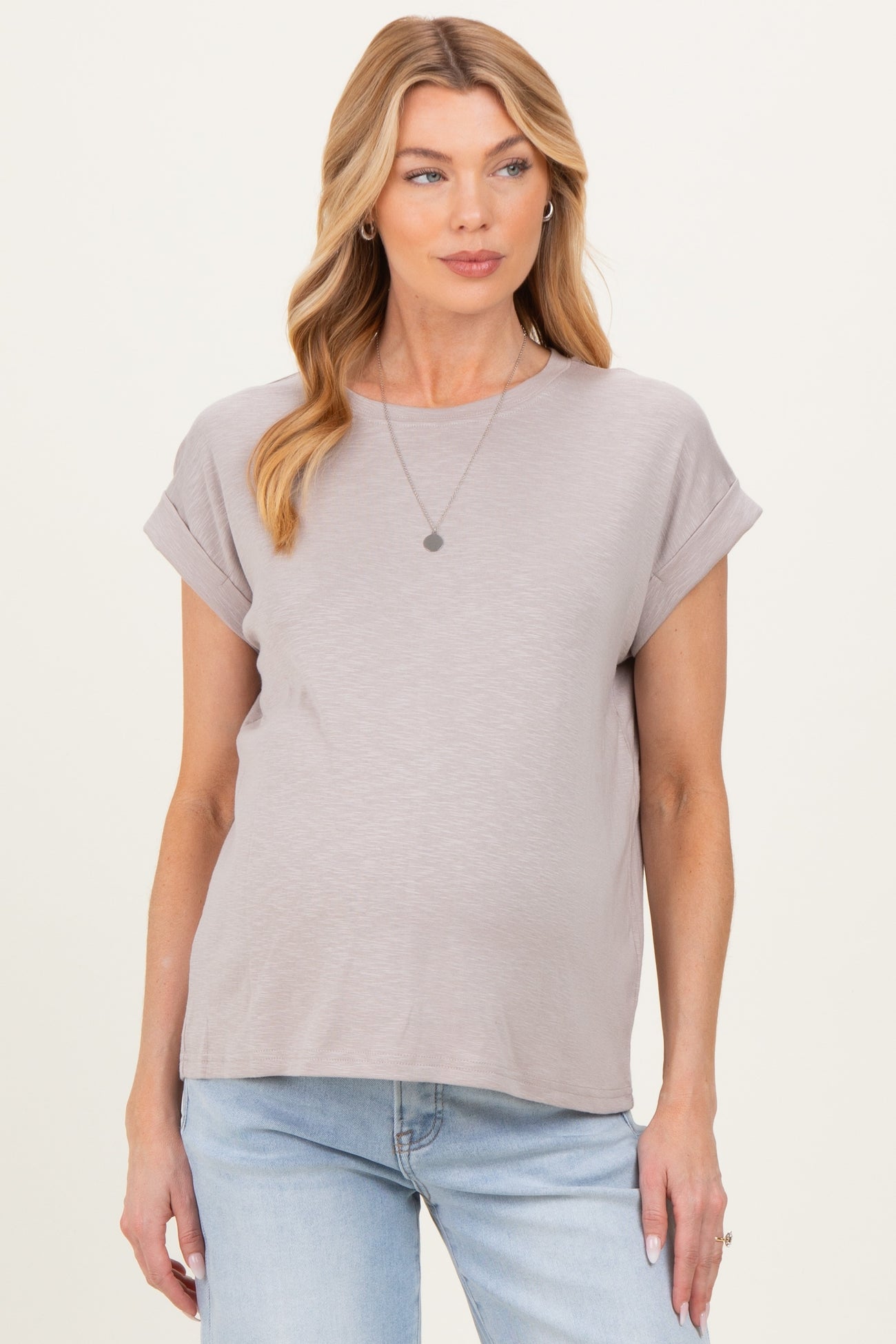 woman wearing a light gray short sleeve maternity top with rolled cuffs and a visible baby bump