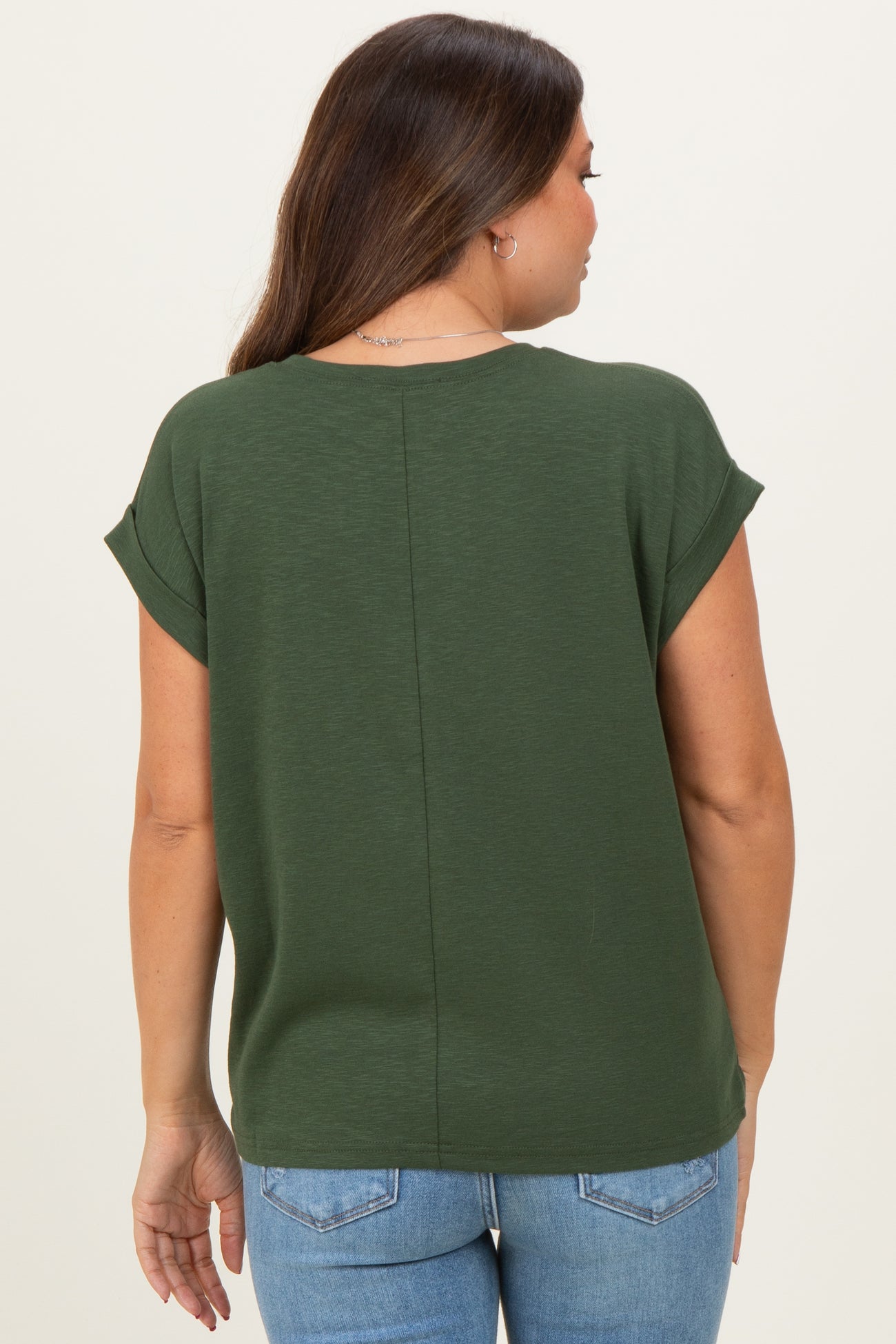 woman wearing a dark green maternity top with rolled sleeves viewed from the back, paired with light blue jeans