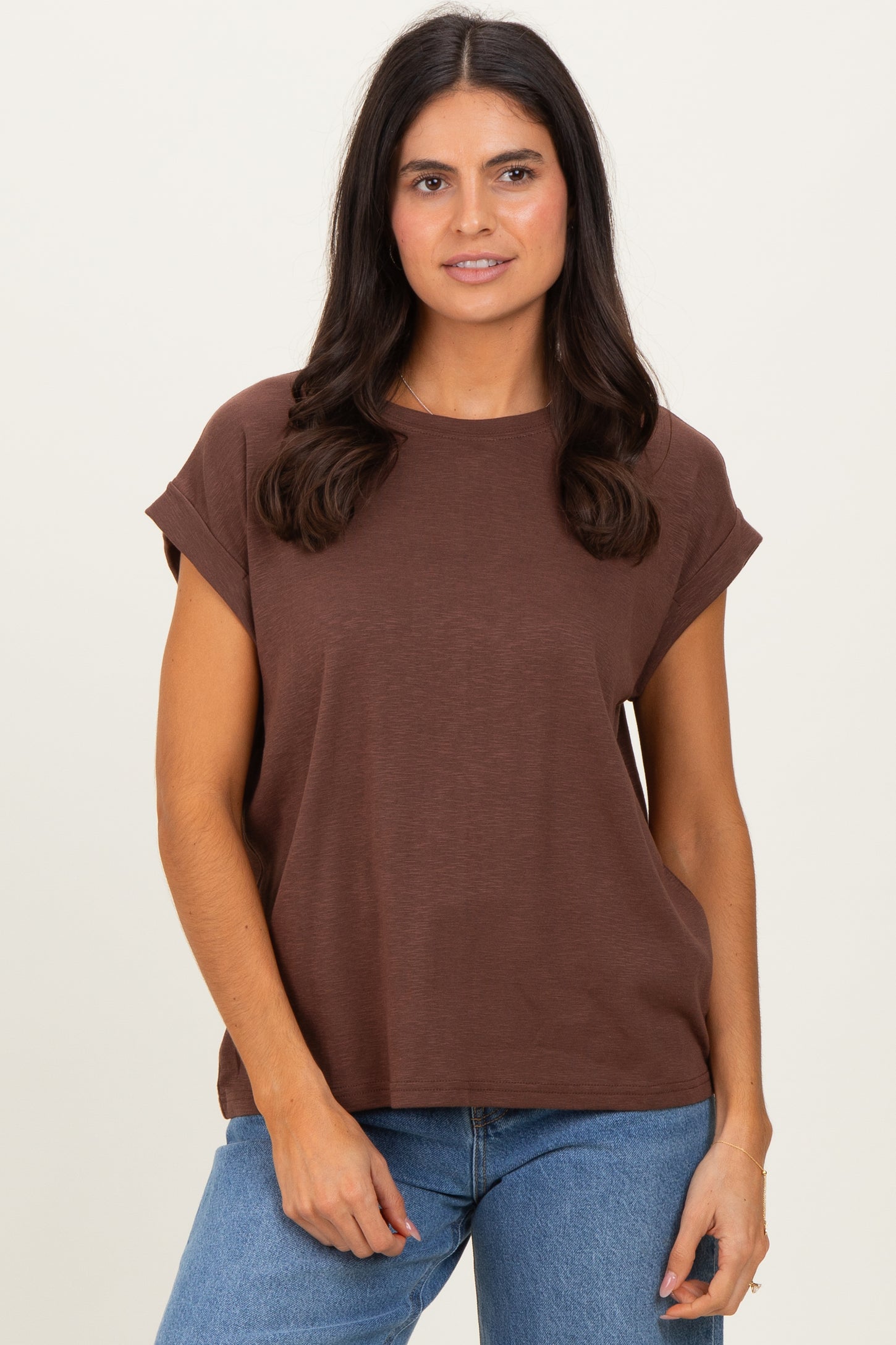 woman wearing a brown short sleeve casual top with rolled cuffs and a relaxed fit, paired with blue jeans