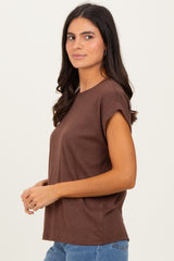 woman wearing a brown short sleeve top with rolled cuffs and a relaxed fit, styled with blue jeans