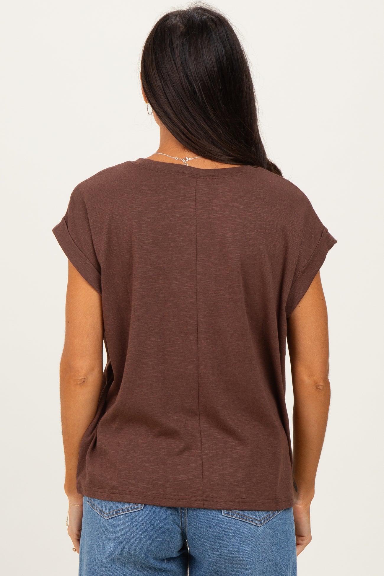 woman wearing a brown short sleeve top with rolled sleeves, viewed from the back