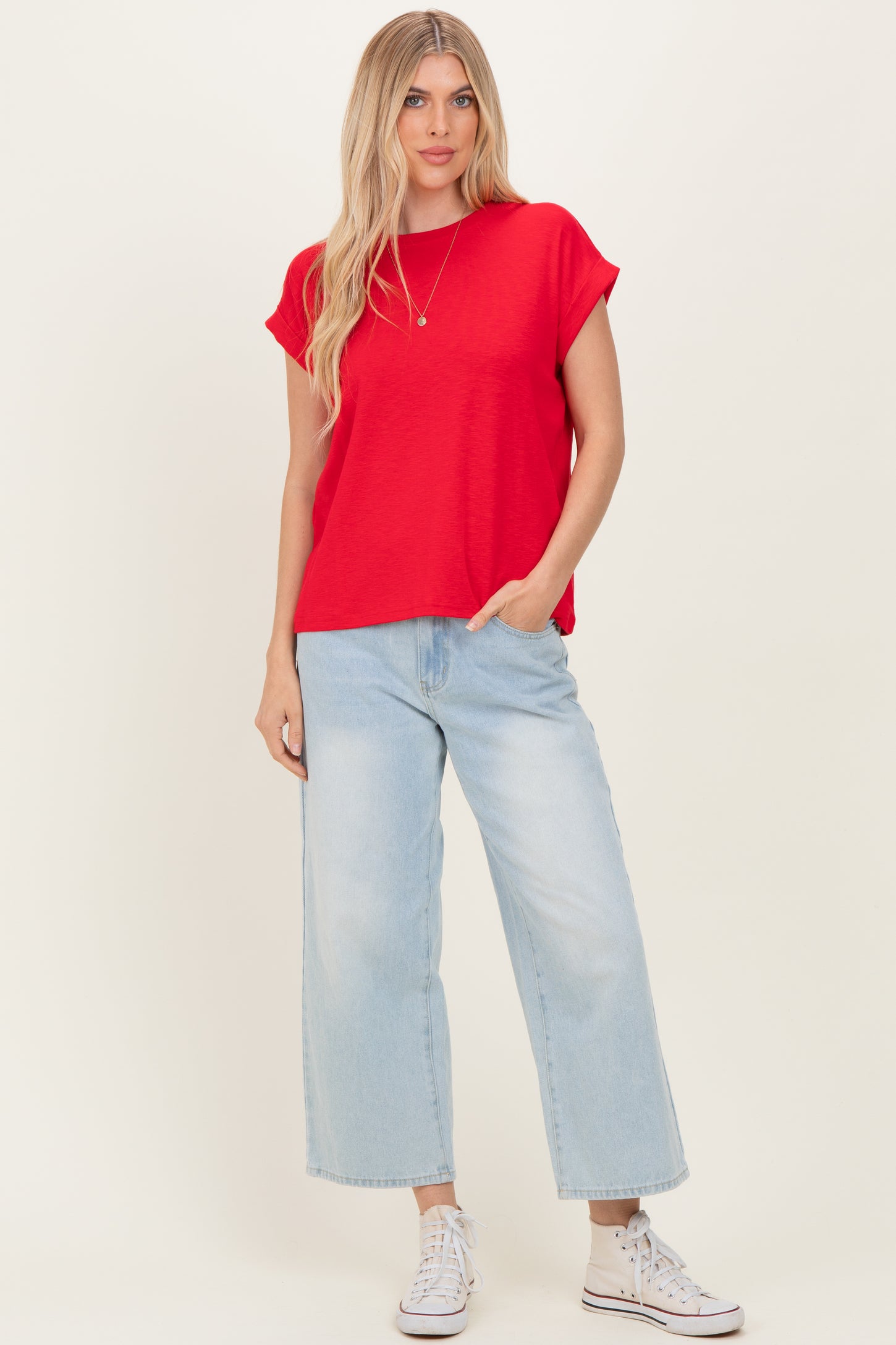 woman wearing a red short sleeve top and light blue wide-leg jeans with white sneakers