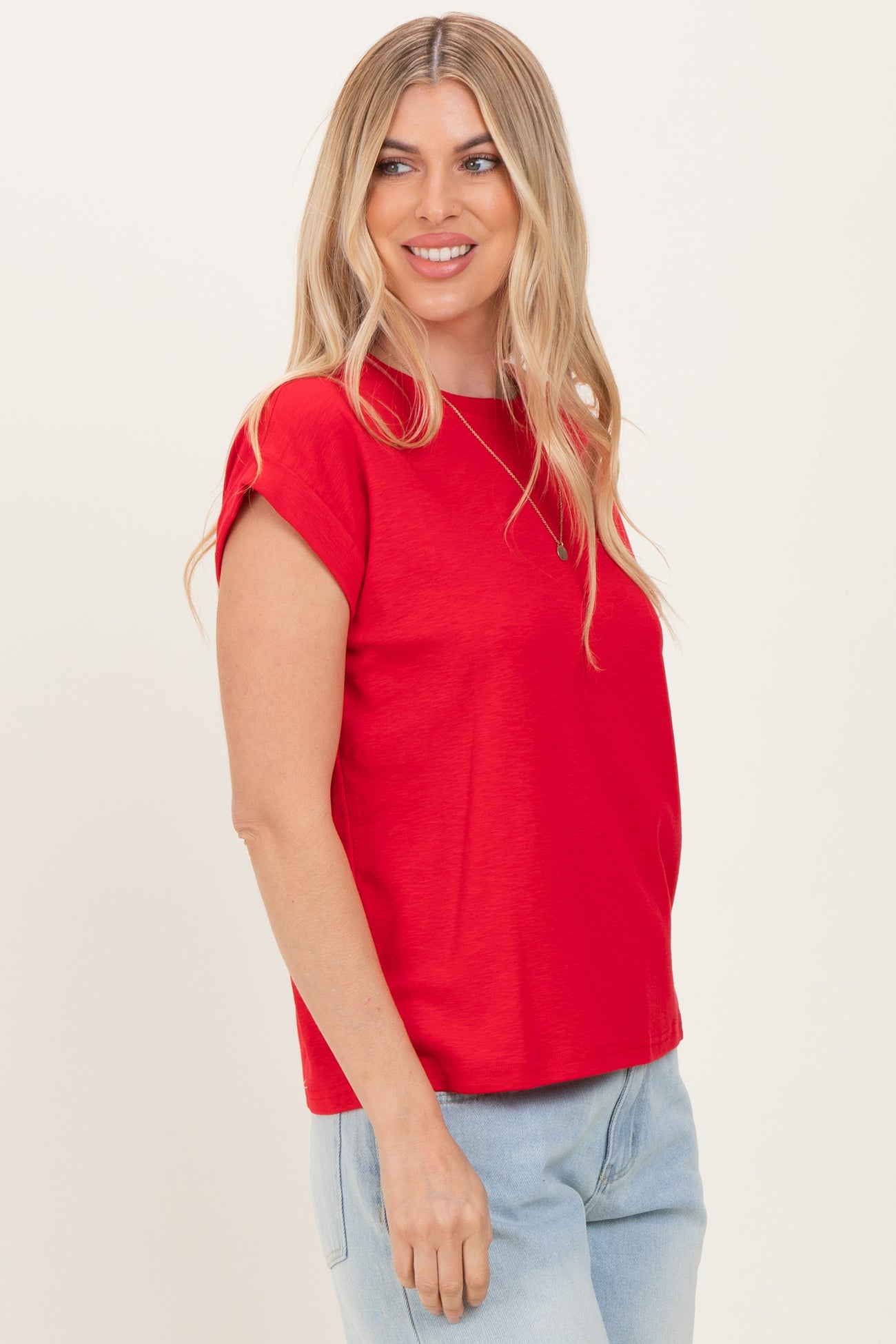 woman wearing a red short sleeve top with rolled cuffs and relaxed fit, styled with light blue jeans