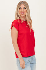 woman wearing a red short sleeve top with rolled cuffs and relaxed fit, styled with light blue jeans