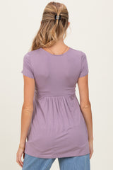 woman wearing a lavender short sleeve maternity top with a gathered waist and a relaxed fit from the back