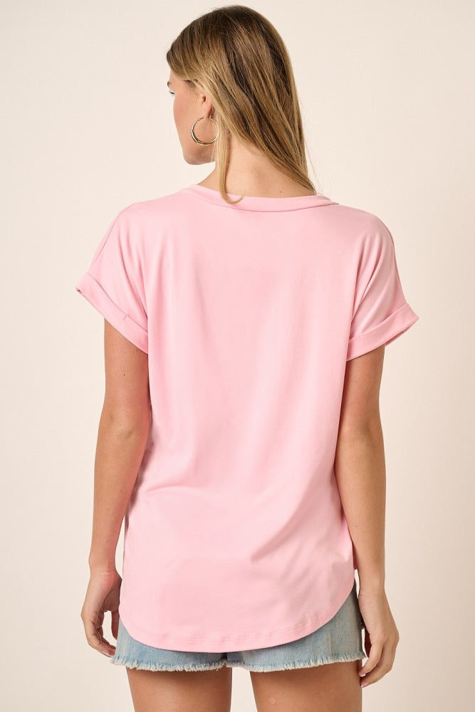 woman wearing a soft pink short sleeve top with rolled cuffs and a relaxed fit, styled with denim shorts