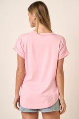 woman wearing a soft pink short sleeve top with rolled cuffs and a relaxed fit, styled with denim shorts