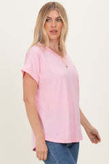 woman wearing a light pink short sleeve relaxed fit top with a chest pocket and a v-neckline