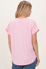 woman wearing a light pink short sleeve top with a relaxed fit and rolled sleeves, viewed from the back