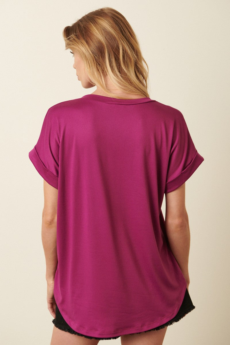 woman wearing a fuchsia short sleeve top with rolled sleeves and a loose fit, shown from the back