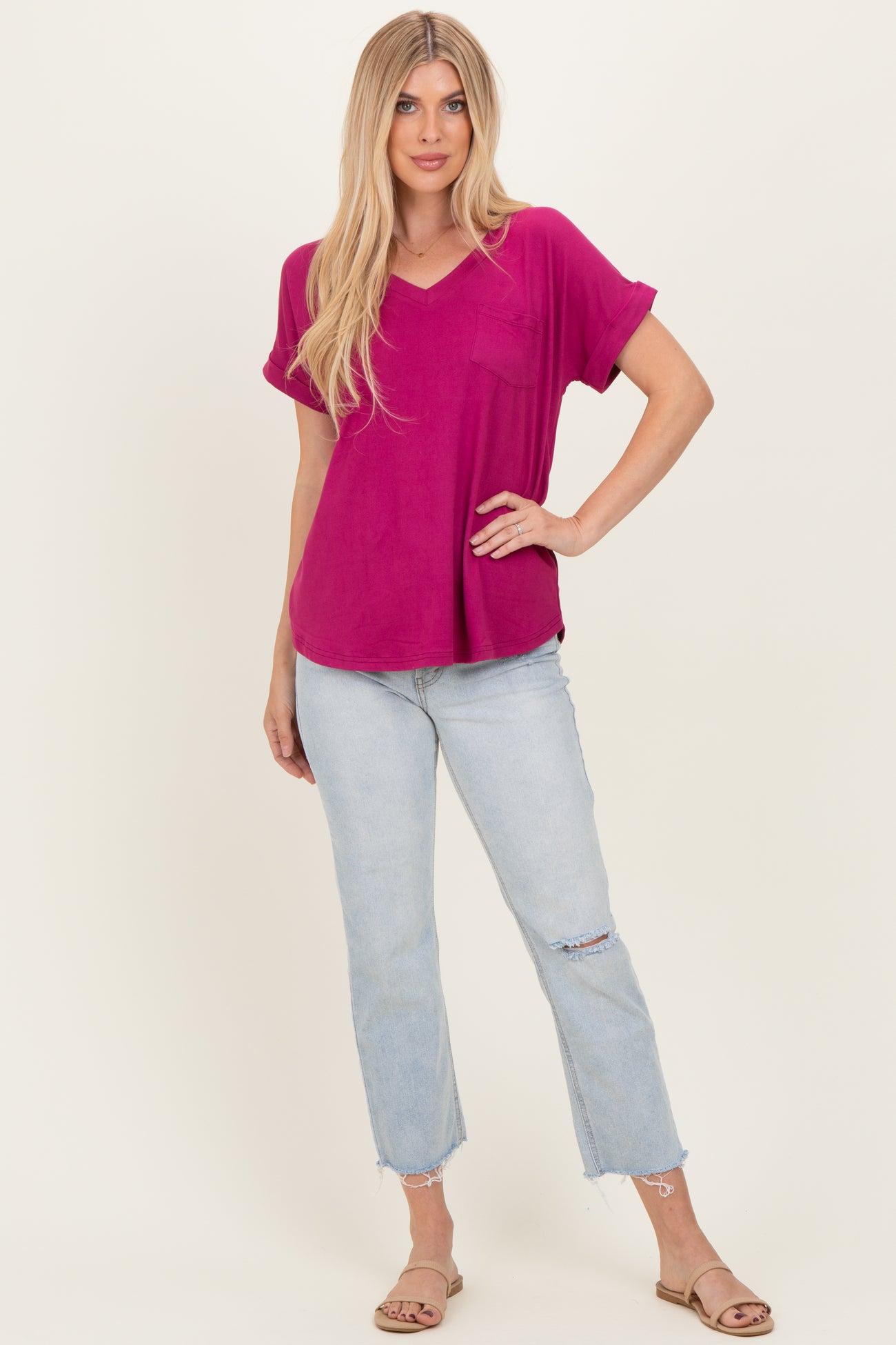 woman wearing a magenta short sleeve v-neck top with a pocket and light wash distressed jeans