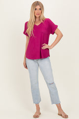 woman wearing a magenta short sleeve v-neck top with a pocket and light wash distressed jeans