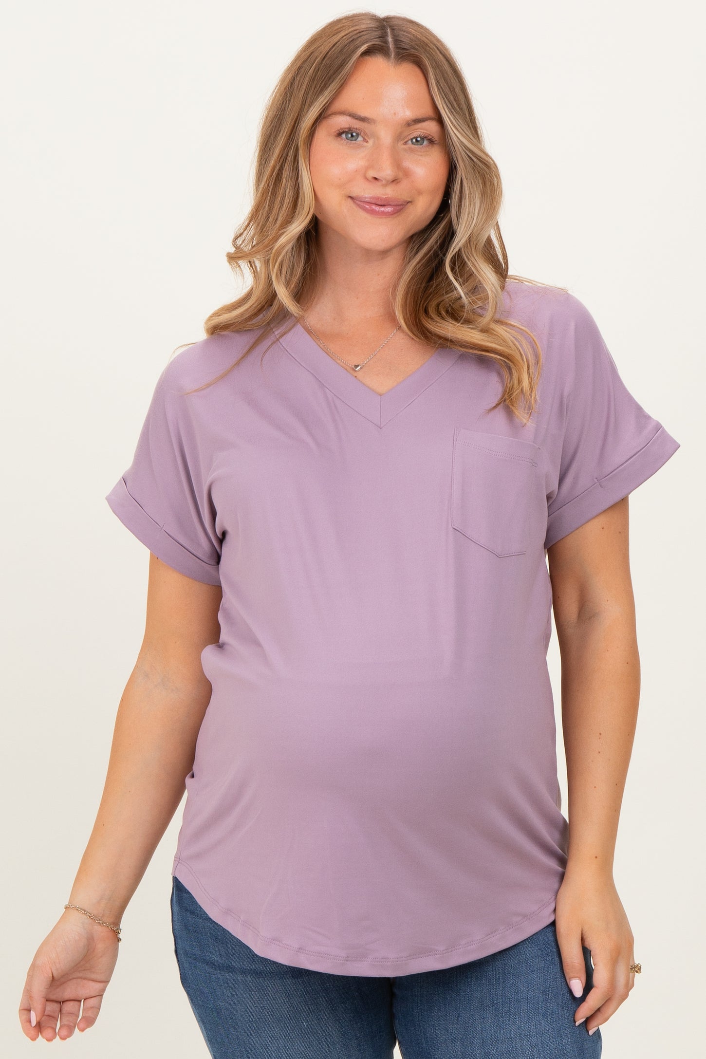 woman wearing a lavender short sleeve maternity top with a v-neck and pocket, showing her baby bump