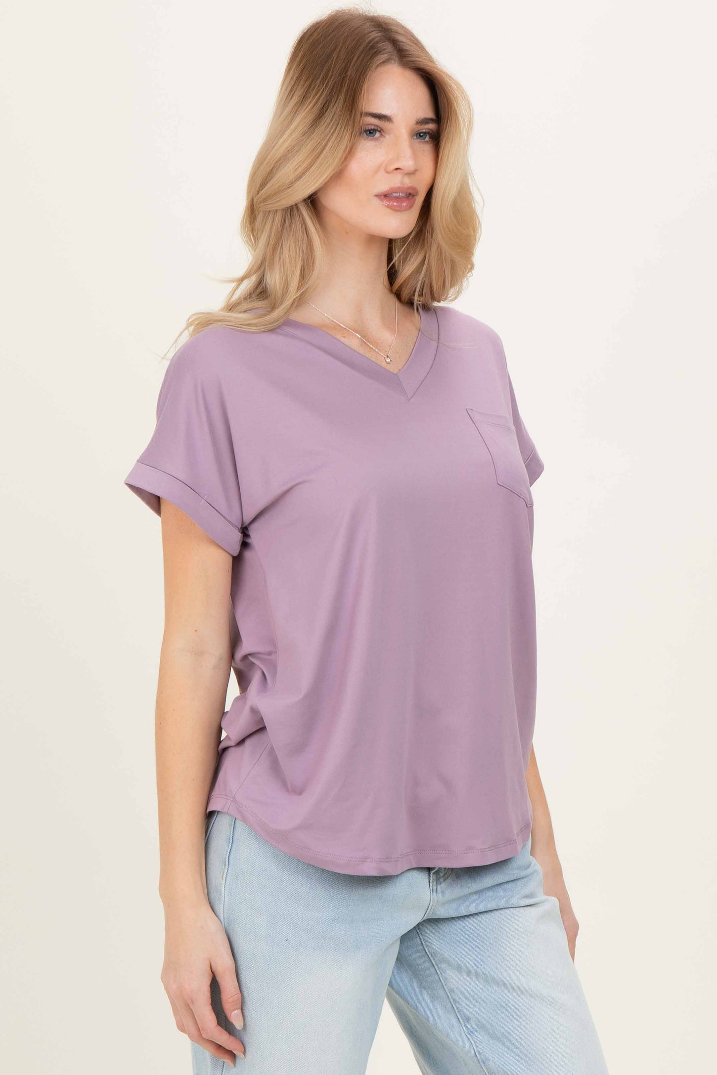 woman wearing a lavender v-neck loose-fit top with rolled sleeves and a front pocket