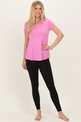woman wearing a hot pink short sleeve top and black leggings, posing with one hand on her hip