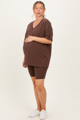 woman wearing a brown oversized v-neck maternity t-shirt and matching biker shorts, showing her baby bump