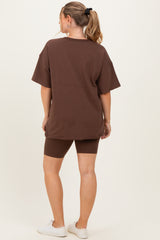 woman wearing a brown oversized t-shirt and matching biker shorts, showing a comfortable maternity outfit from behind
