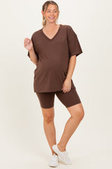 woman wearing a brown maternity v-neck oversized t-shirt and brown maternity bike shorts with a baby bump visible