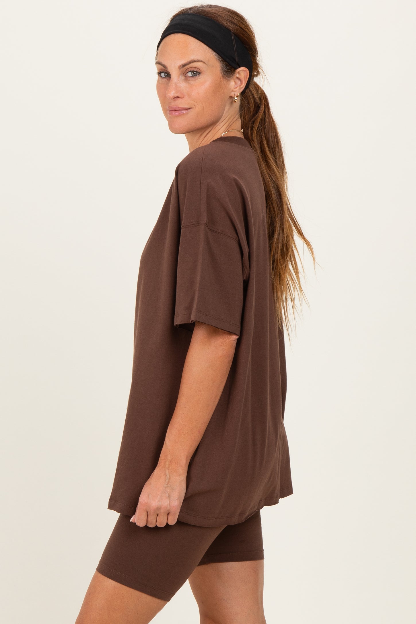 woman wearing a brown oversized t-shirt and matching bike shorts, styled with a headband