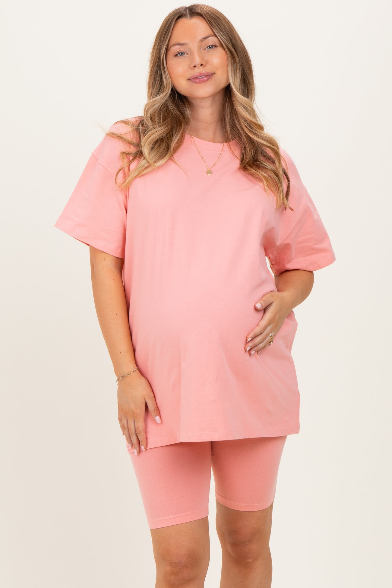 woman wearing a pink maternity t-shirt and matching bike shorts, showing her baby bump