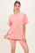 woman wearing a coral oversized t-shirt and matching bike shorts, posing with one hand on the shirt