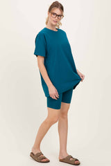 woman wearing a teal oversized t-shirt and matching biker shorts, styled with glasses and sandals