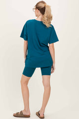 woman wearing a teal oversized t-shirt and matching bike shorts, viewed from the back