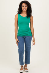 woman wearing a green sleeveless top paired with light blue straight-leg jeans and black slip-on shoes