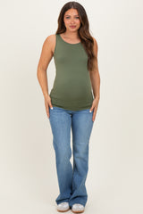 woman wearing a green maternity tank top and blue flared jeans, showcasing a baby bump