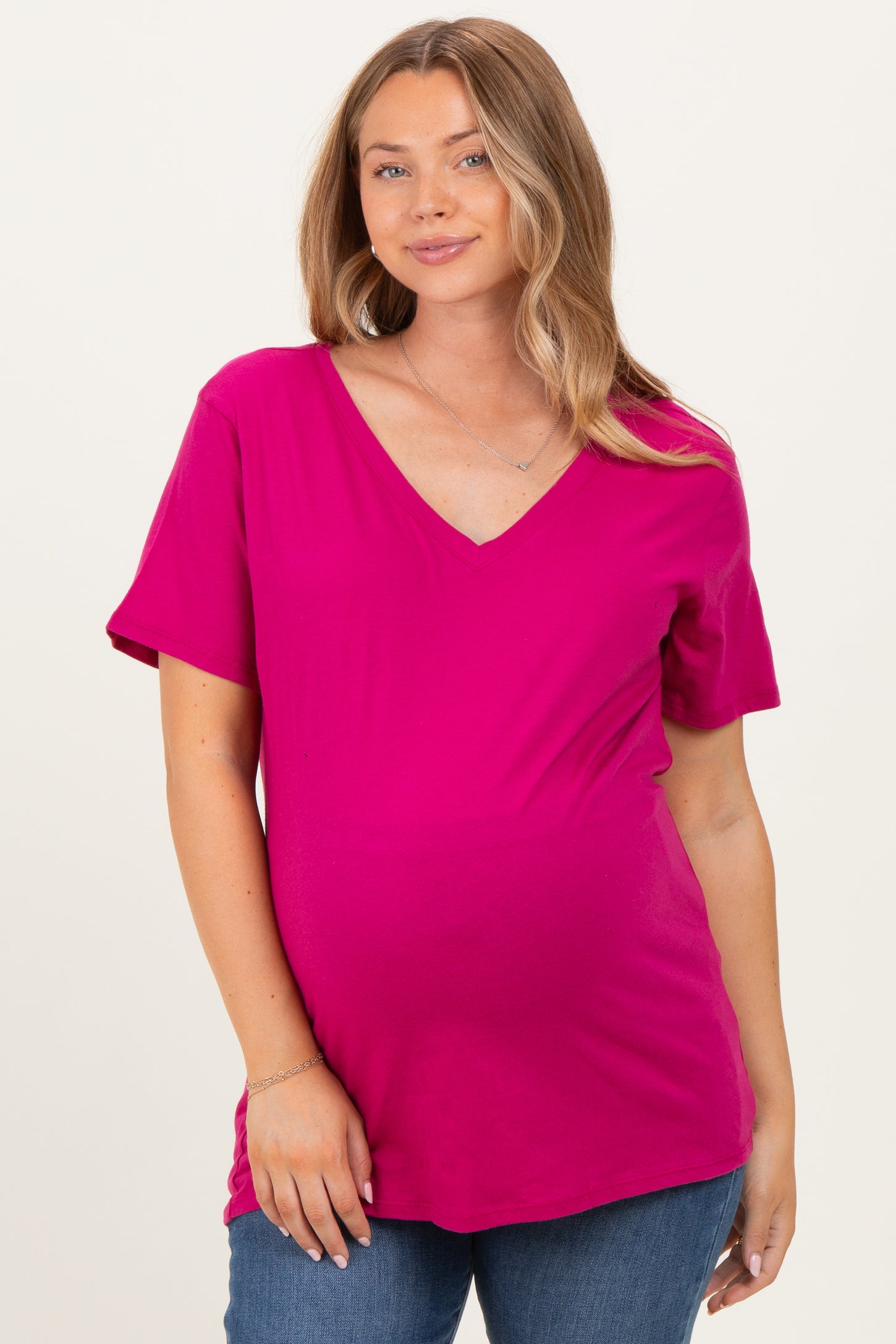 woman wearing a hot pink v-neck short sleeve maternity top and showing her baby bump