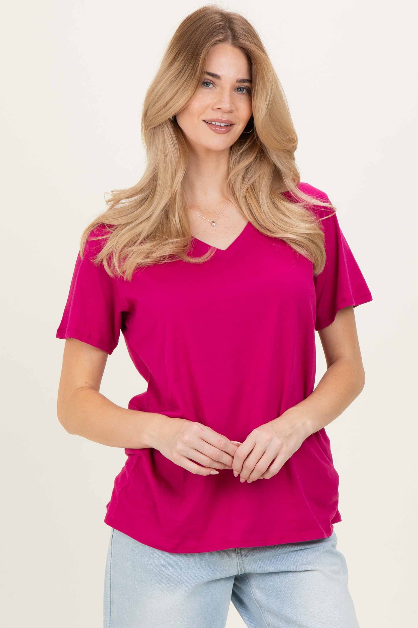 woman wearing a bright pink v-neck t-shirt with short sleeves and a relaxed fit