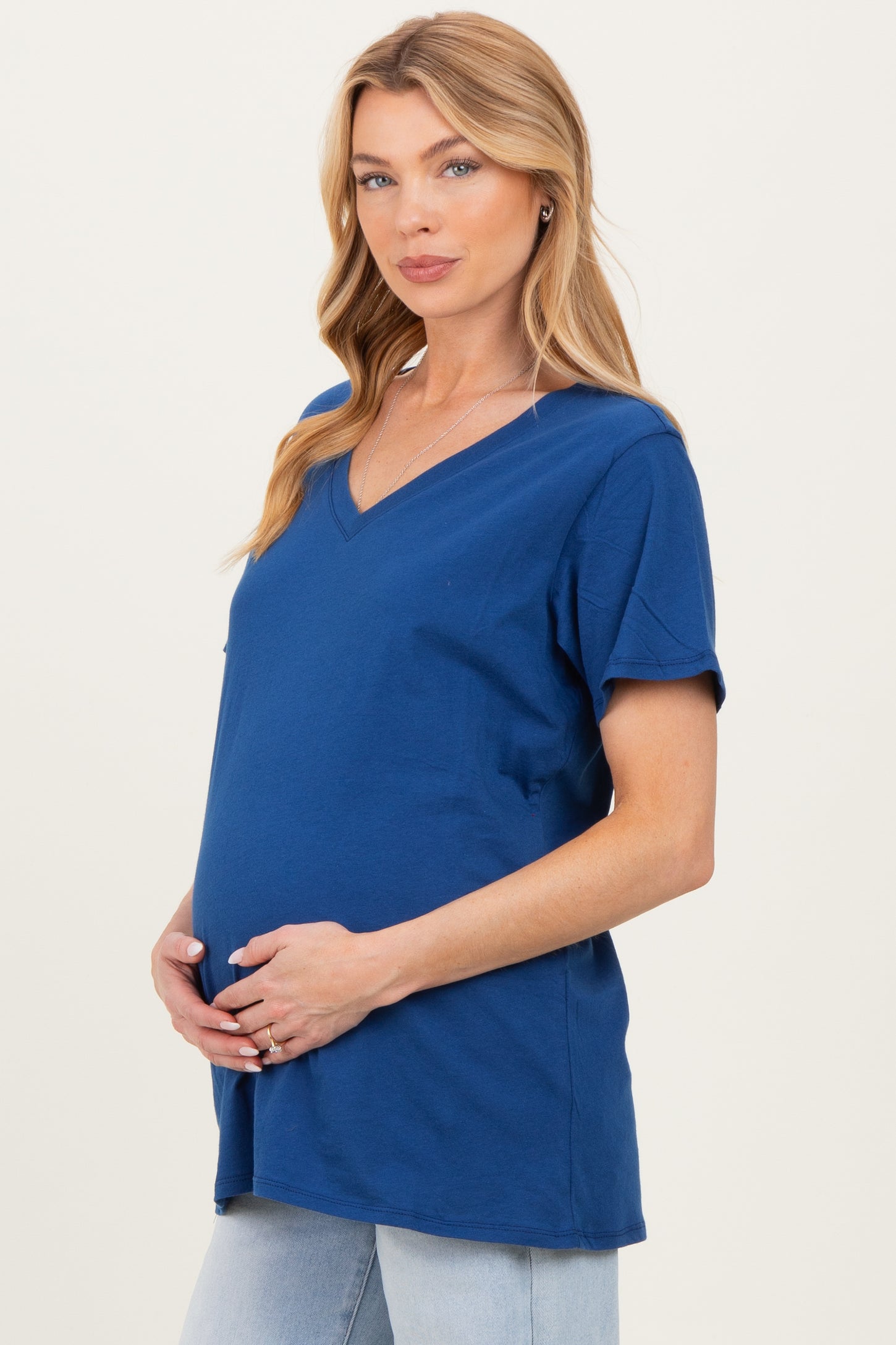woman wearing a navy blue v-neck maternity top and holding her baby bump