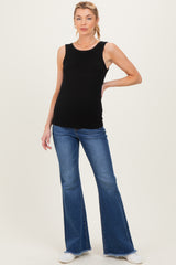 woman wearing a black ribbed maternity tank top and blue flared jeans, showcasing her baby bump
