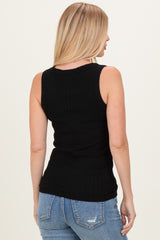 woman wearing a black ribbed sleeveless top with a fitted silhouette, paired with light blue jeans