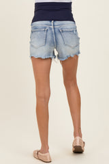 woman wearing maternity light blue distressed denim shorts with frayed hemline, showing a fitted design from the back