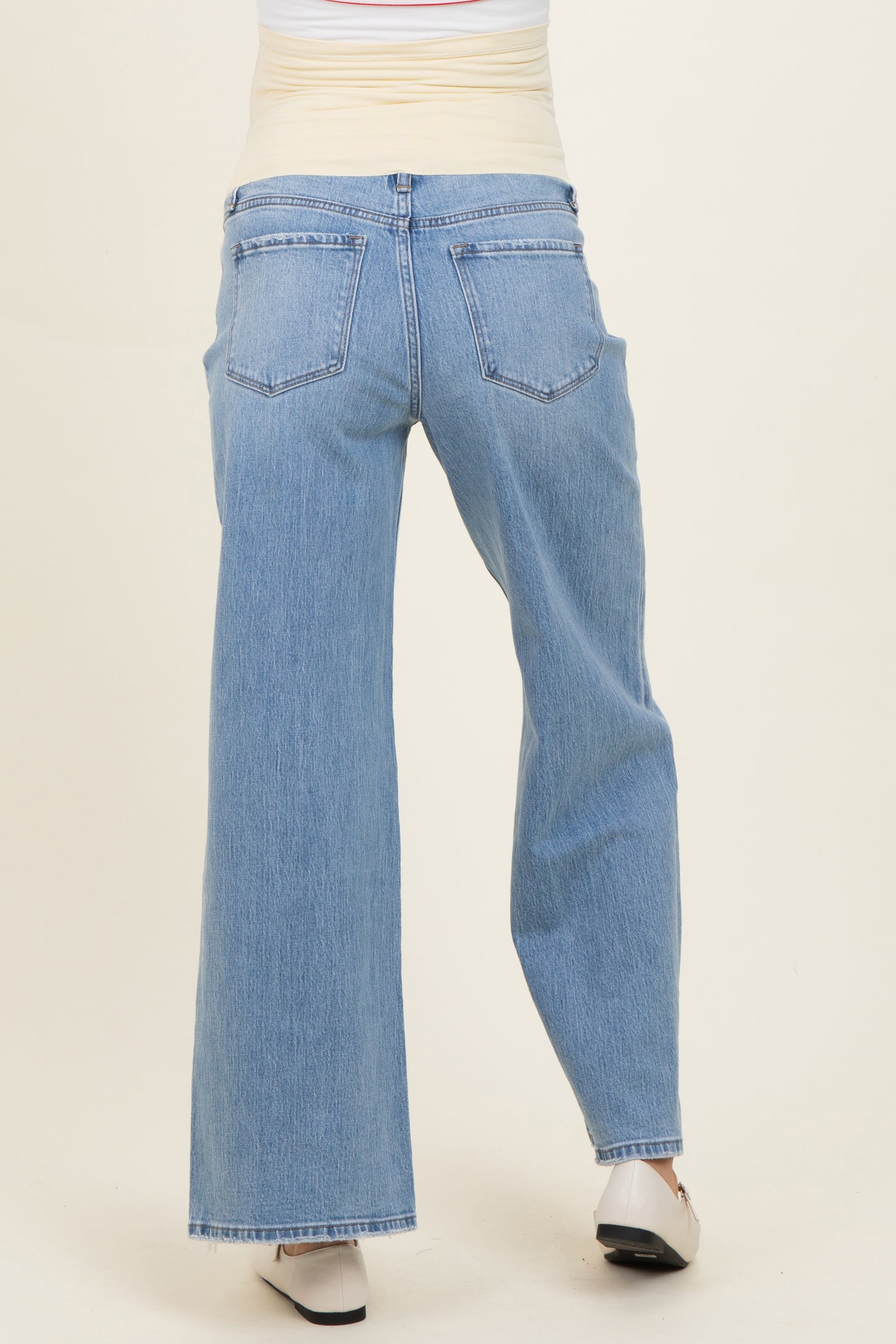 woman wearing light wash maternity jeans with a wide-leg fit, seen from the back